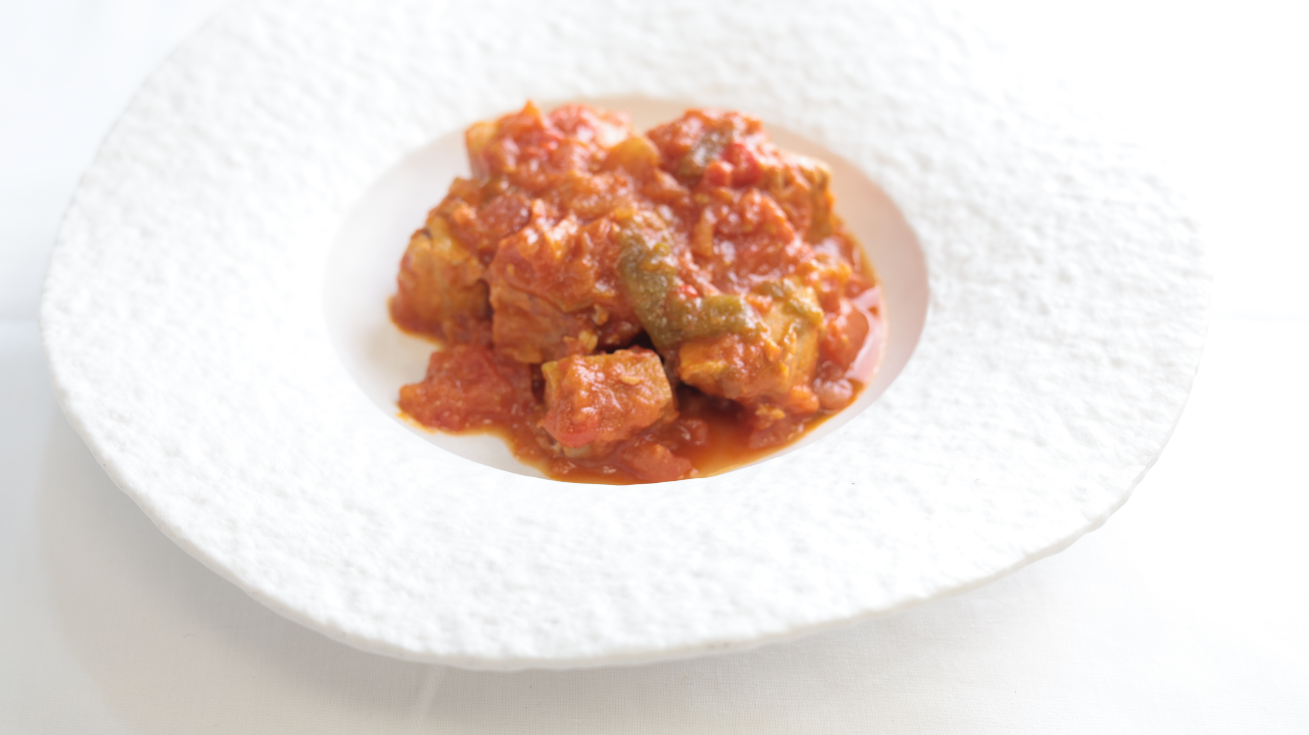 Atún en tomate servido en plato blanco